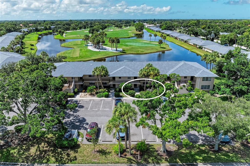 An aerial view shows a multi-story apartment building with a parking lot and golf course — 6999 W COUNTRY CLUB DRIVE N UNIT 123, SARASOTA, FL