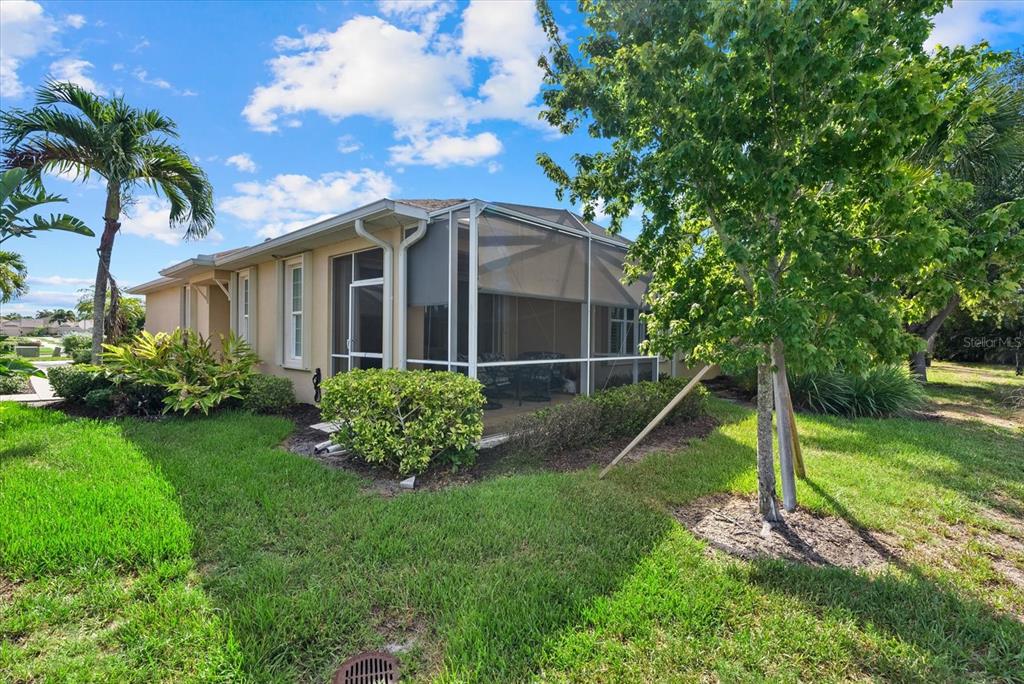 A beige house features a screened-in lanai, a palm tree, and a manicured lawn — 395 CAPULET DRIVE, VENICE, FL