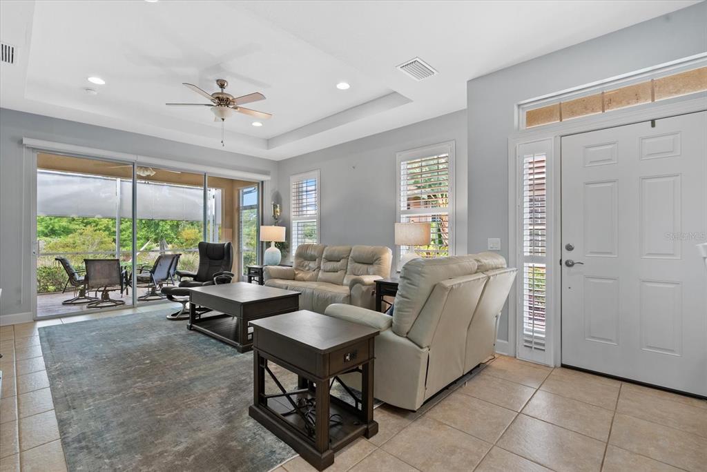A living room with tile floors, a tray ceiling, and sliding doors opening to a patio — 395 CAPULET DRIVE, VENICE, FL