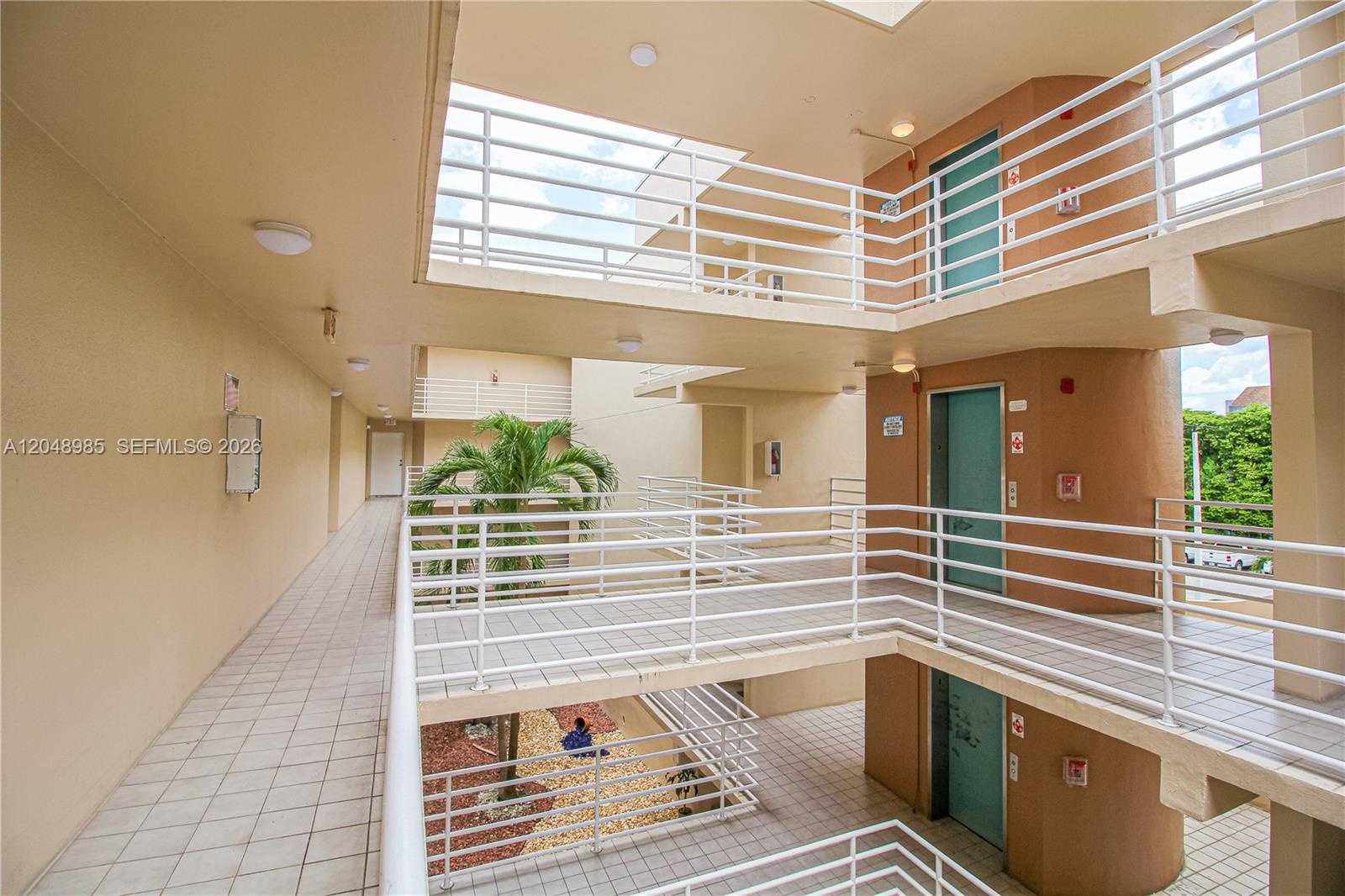 An open-air apartment building corridor features multiple levels with white railings and tiled walkways — 8050 NW 8th St # 1306, Miami FL 33126, MIAMI, FL