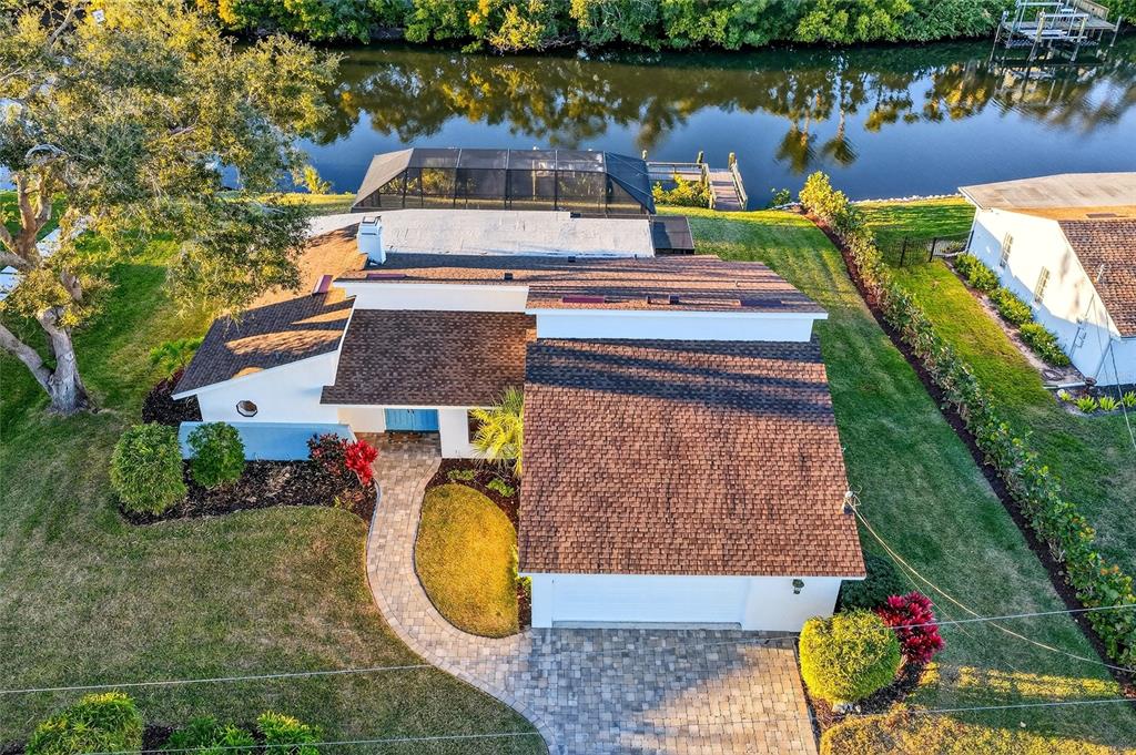 An aerial view shows a house with a brown shingled roof, paver driveway, and pool — 5424 AMERICA DRIVE, SARASOTA, FL