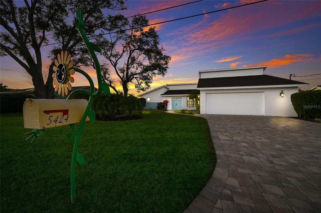 A single-story house with a white exterior, a paved driveway, and a decorative sunflower mailbox — 5424 AMERICA DRIVE, SARASOTA, FL