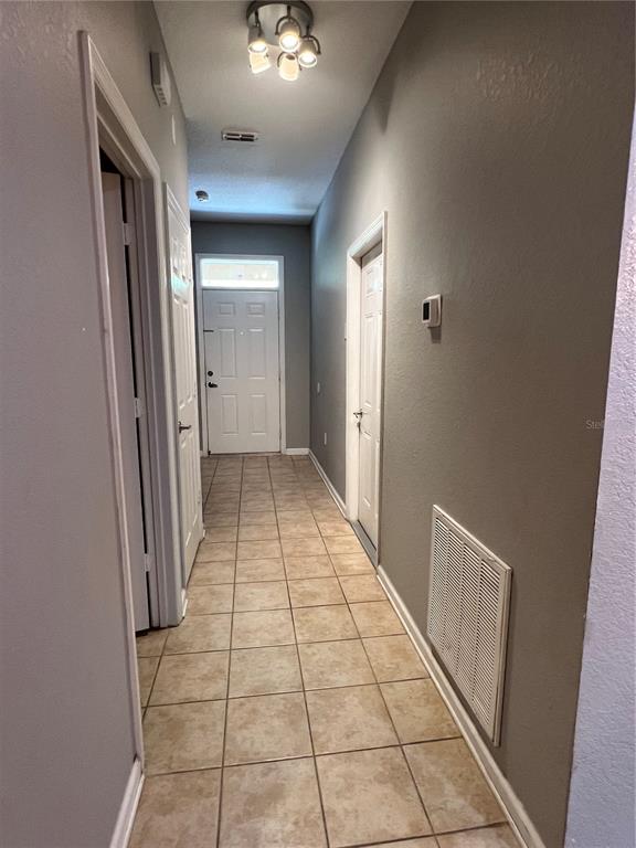 A hallway with light tile flooring leads to a white front door — 8210 DOWN ROYAL ROAD, TAMPA, FL