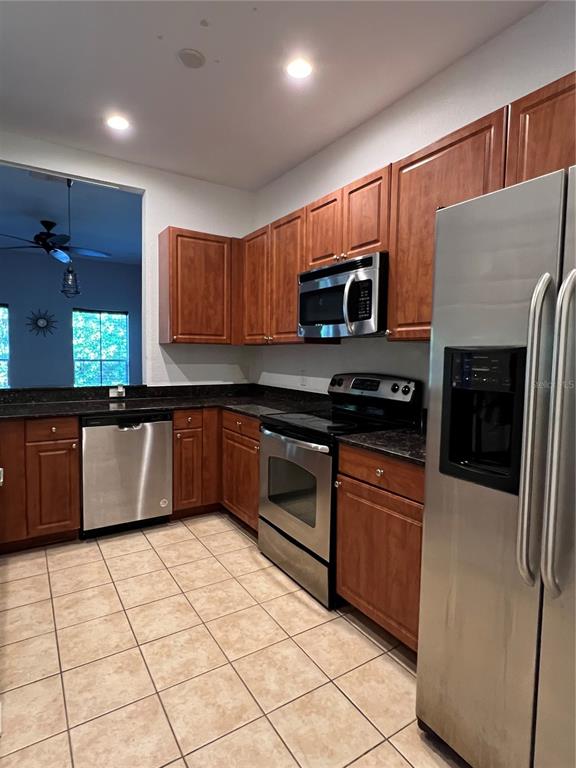 A kitchen features wood cabinets, stainless steel appliances, and light-colored tile flooring — 8210 DOWN ROYAL ROAD, TAMPA, FL