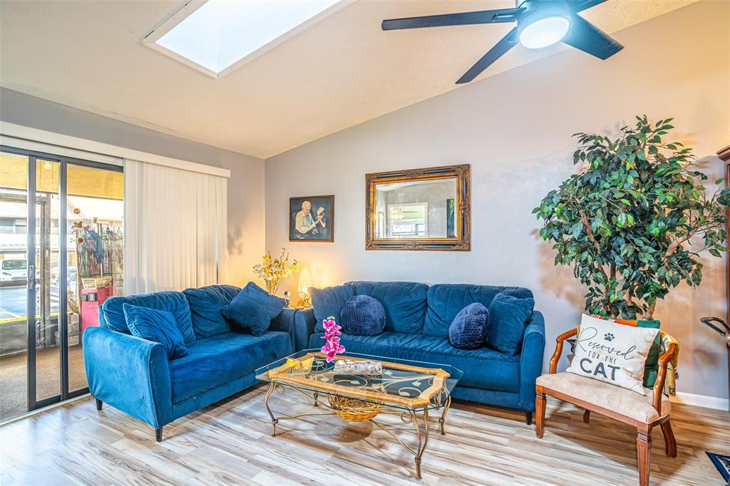 A living room features two blue sofas, a glass coffee table, and a decorative chair — 15 CHARLTON DRIVE UNIT 15, LAKE PLACID, FL