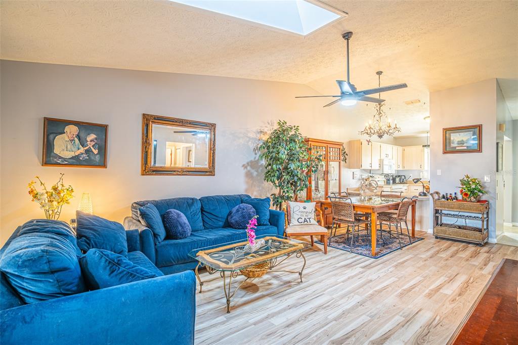 A living room with blue sofas, a glass coffee table, and an adjacent dining area — 15 CHARLTON DRIVE UNIT 15, LAKE PLACID, FL