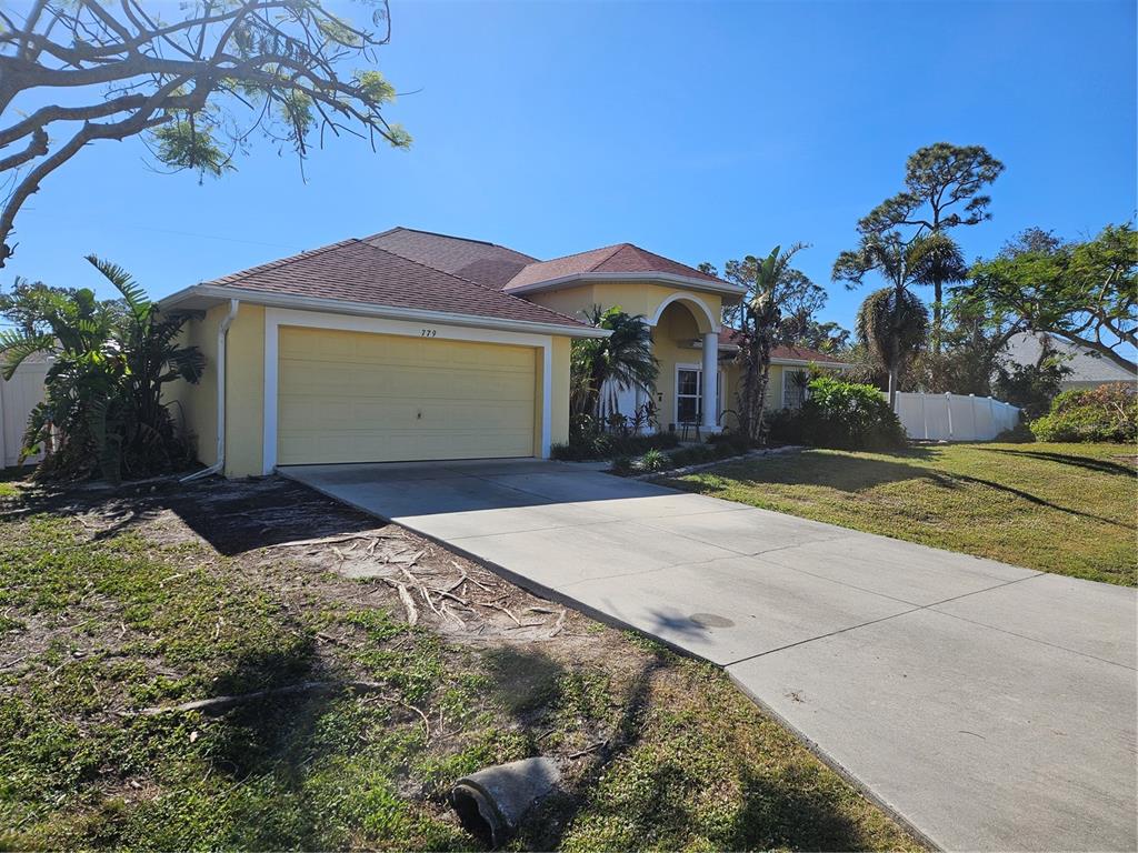 A yellow single-story house with a two-car garage and a concrete driveway — 779 NECTAR ROAD, VENICE, FL