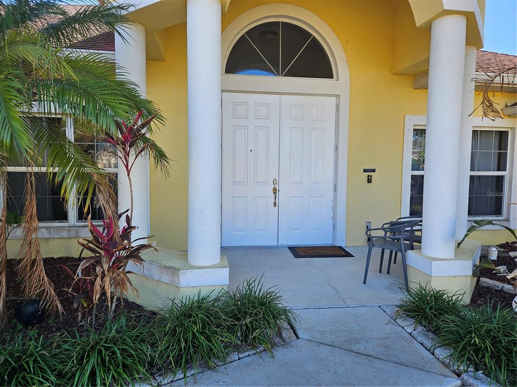 A yellow house exterior features a white double front door with a semi-circular transom window — 779 NECTAR ROAD, VENICE, FL