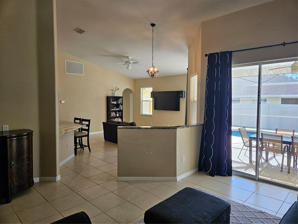 A living room with tile floors, a half-wall, and a sliding glass door to a pool — 779 NECTAR ROAD, VENICE, FL