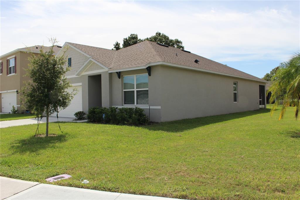 A single-story suburban house with a tan stucco exterior, a shingled roof, and a lawn — 2917 CANARY LANE, TAVARES, FL