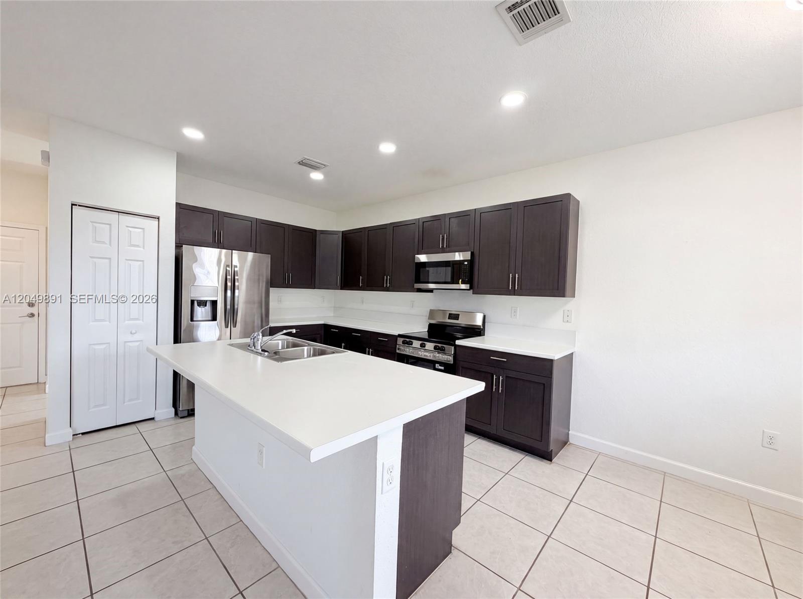 A kitchen features dark wood cabinets, white countertops, a center island, and stainless steel appliances — 12858 SW 228th St, Miami FL 33170, MIAMI, FL