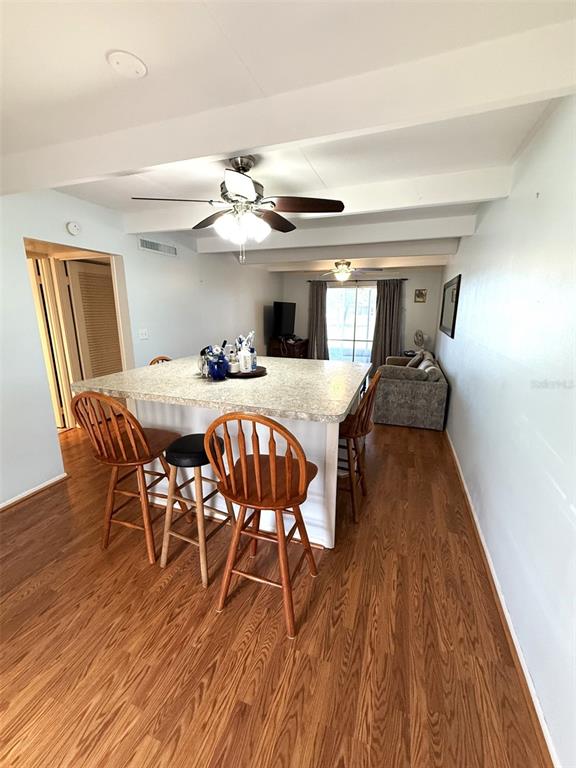 A kitchen island with bar stools sits in an open-concept room with wood-look flooring — 3013 CLUB CIRCLE, LAKESHORE, FL