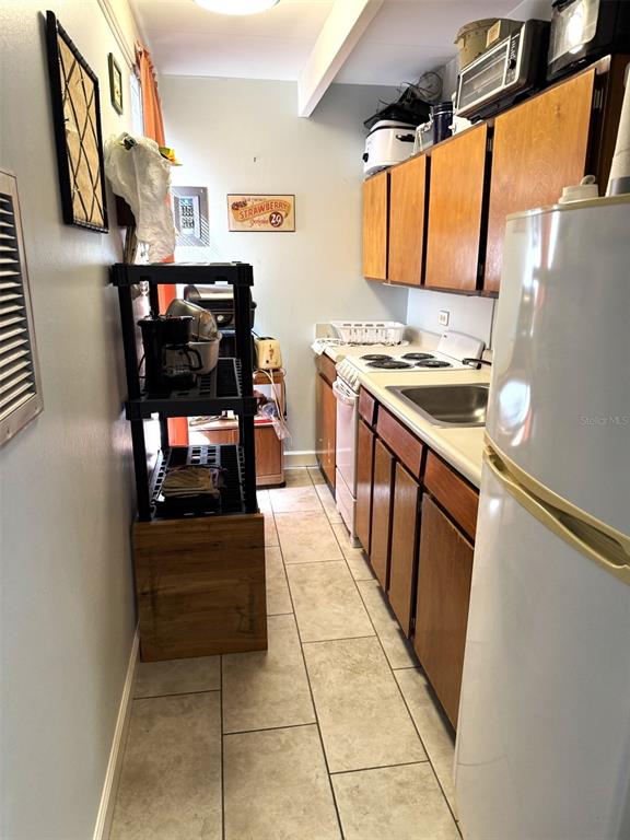 A narrow kitchen features wood cabinets, a white refrigerator, a stove, and a black shelf — 3013 CLUB CIRCLE, LAKESHORE, FL