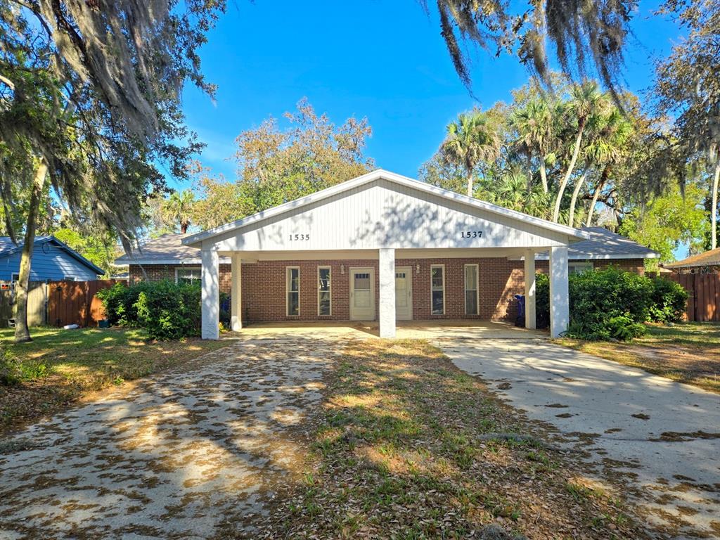 A single-story brick duplex with a shared covered front porch and a concrete driveway — 1537 MANGO TREE DRIVE, EDGEWATER, FL