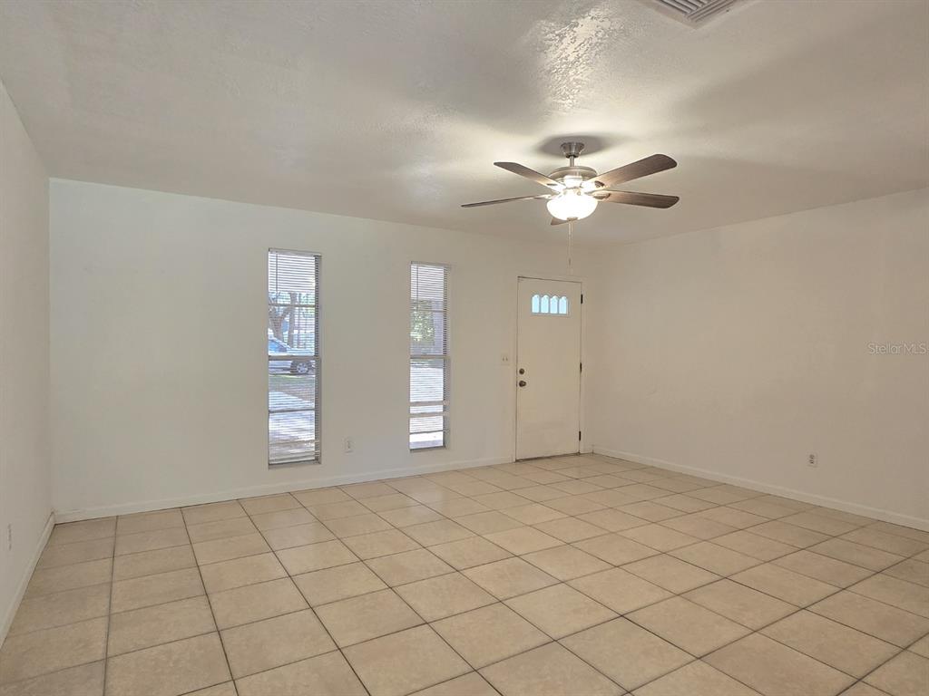 An empty room with white walls, tiled floors, a ceiling fan, and two narrow windows — 1537 MANGO TREE DRIVE, EDGEWATER, FL