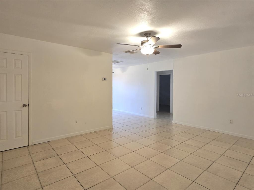An empty room with white walls, a ceiling fan, and light-colored tile flooring — 1537 MANGO TREE DRIVE, EDGEWATER, FL