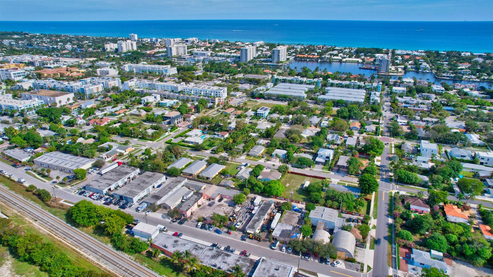 An aerial view shows a coastal neighborhood with residential homes, commercial buildings, and nearby water — 369 SE 2nd Avenue, Delray Beach FL 33483, DELRAY BEACH, FL