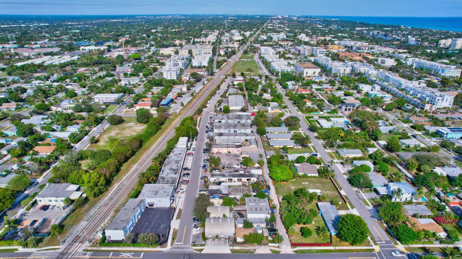 An aerial view shows a city street, railroad tracks, and surrounding residential and commercial buildings — 369 SE 2nd Avenue, Delray Beach FL 33483, DELRAY BEACH, FL