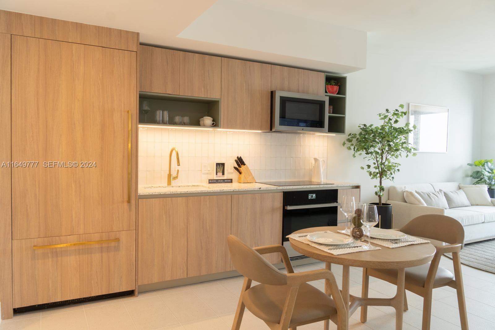 A modern kitchen features light wood cabinetry, a tiled backsplash, and an adjacent dining area — 601 NE 1 Ave # 4704, Miami FL 33132, MIAMI, FL