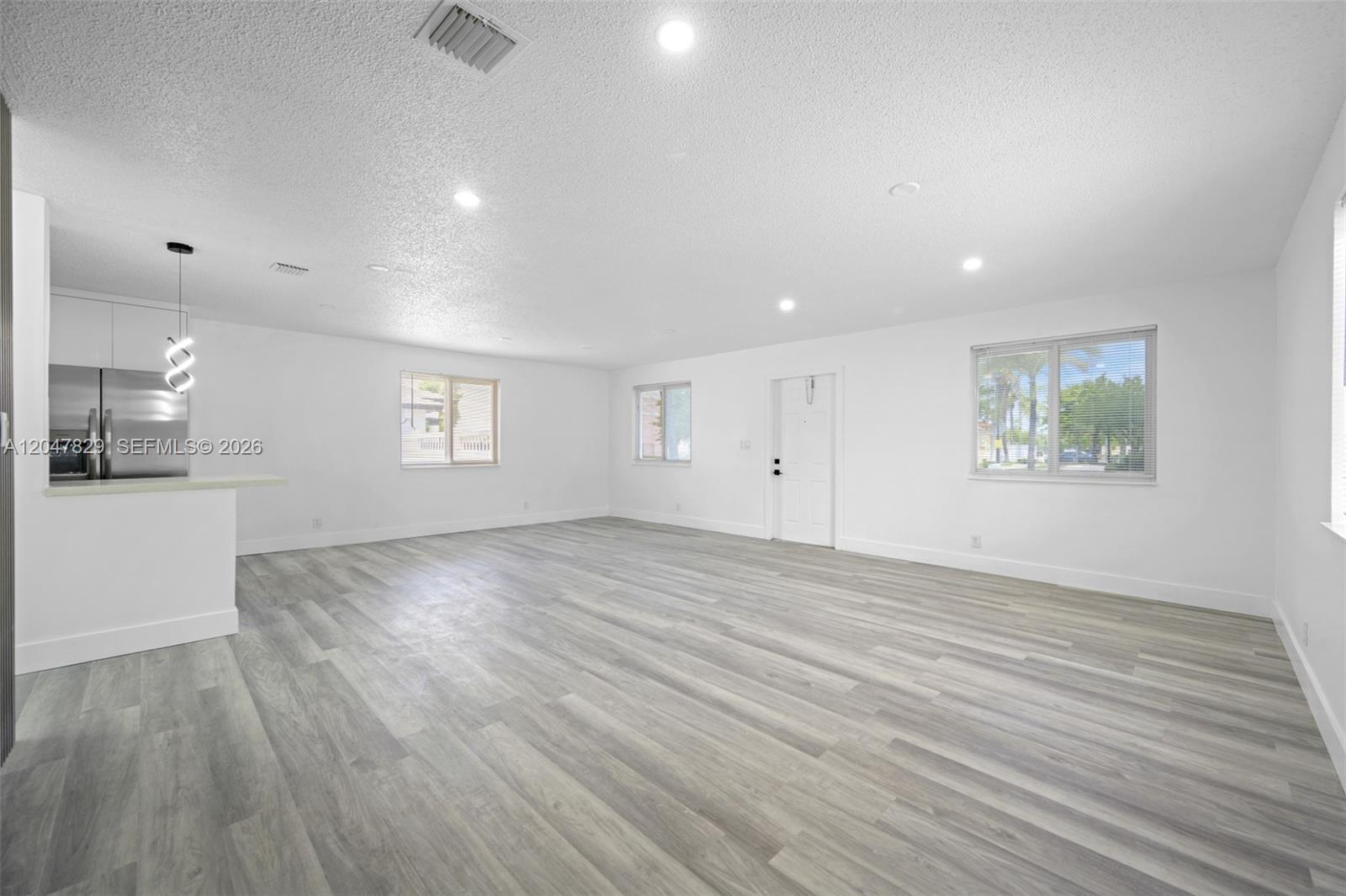 An open-concept living area features white walls, recessed lighting, and light gray wood-look flooring — 5580 Plunkett St, Hollywood FL 33021, HOLLYWOOD, FL