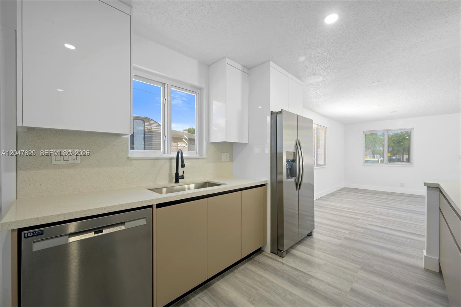 A kitchen features light-colored cabinets, stainless steel appliances, a sink, and wood-look flooring — 5580 Plunkett St, Hollywood FL 33021, HOLLYWOOD, FL