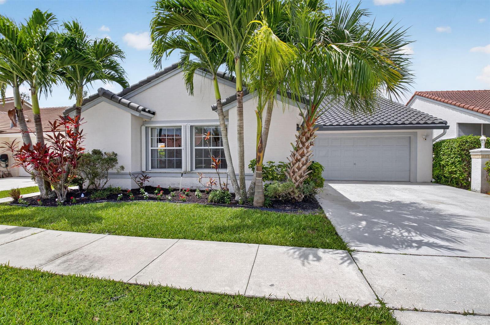 A single-story house with a gray tile roof, light stucco walls, and palm trees — 10048 Country Brook Road, Boca Raton FL 33428, BOCA RATON, FL
