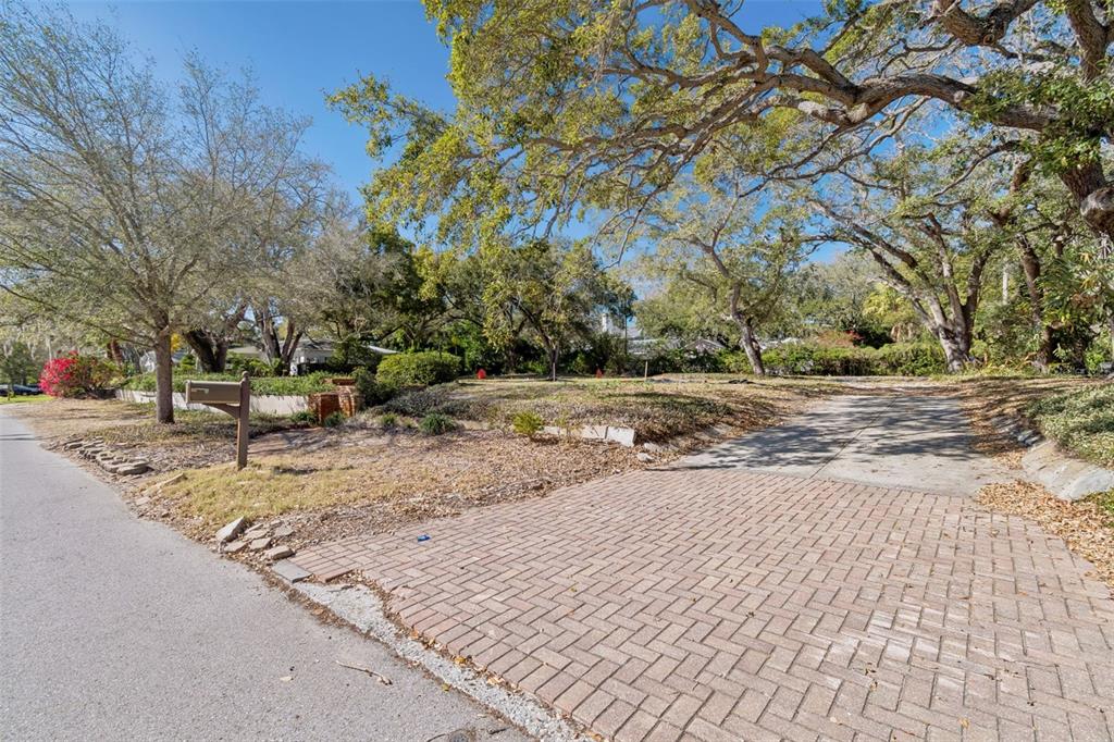 A paved driveway leads to a vacant, tree-shaded residential lot with a brick mailbox — 3015 W FAIR OAKS AVENUE, TAMPA, FL