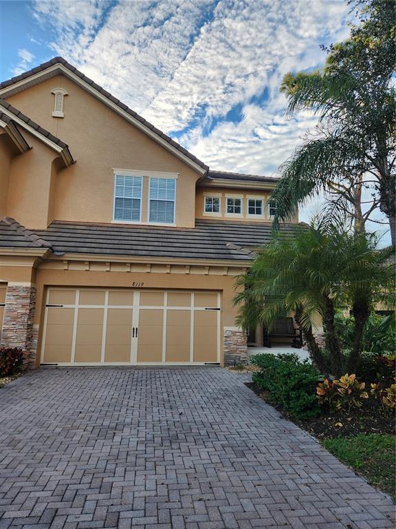 A two-story house with a tan stucco exterior, a paver driveway, and a two-car garage — 8119 VILLA GRANDE COURT, SARASOTA, FL