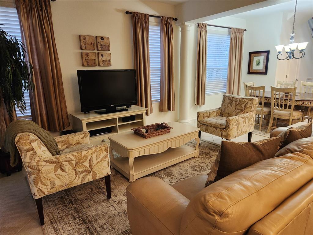 A living room features a television, coffee table, patterned armchairs, and a leather sofa — 8119 VILLA GRANDE COURT, SARASOTA, FL