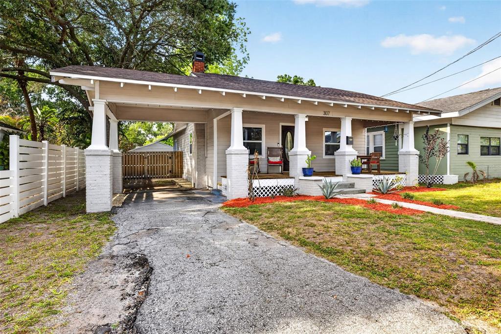 A single-story house with a front porch, carport, and a cracked asphalt driveway — 307 W CHELSEA STREET, TAMPA, FL