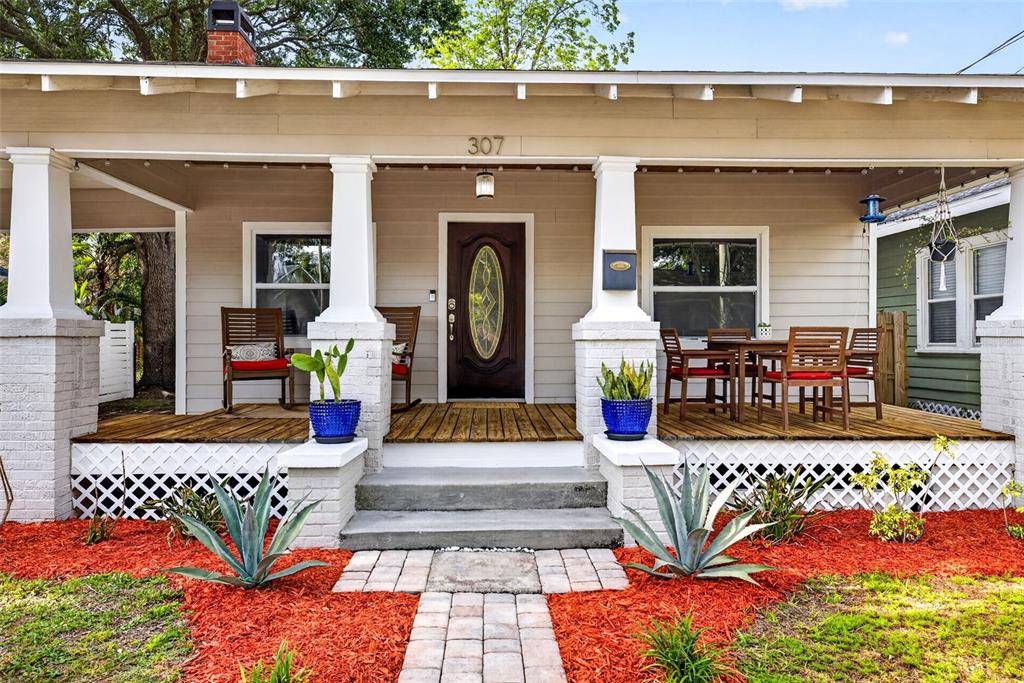 A front porch with a wooden deck, white columns, and rocking chairs faces a landscaped yard — 307 W CHELSEA STREET, TAMPA, FL