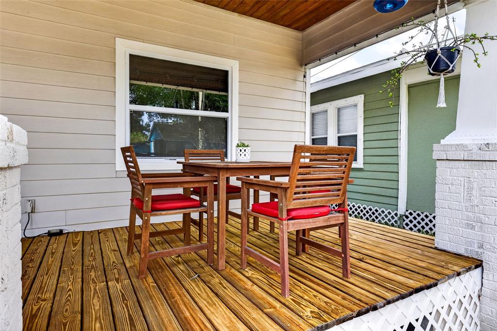 A wooden deck features a dining set with red cushions in front of a house — 307 W CHELSEA STREET, TAMPA, FL