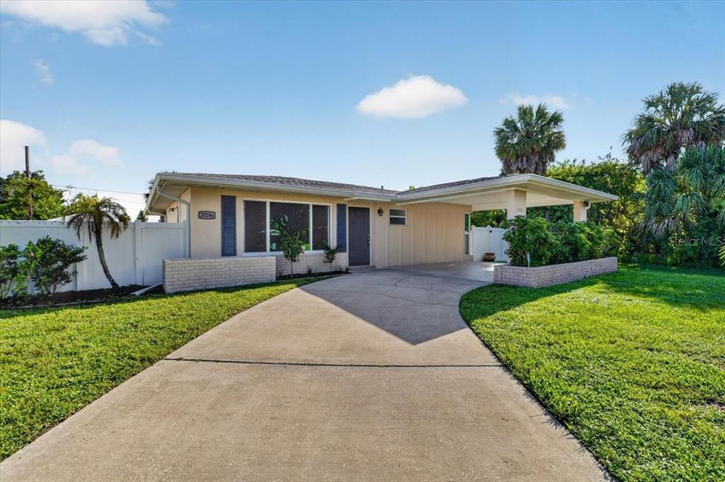 A single-story house with a concrete driveway, a carport, and a white privacy fence — 20286 BENTON AVENUE, PORT CHARLOTTE, FL