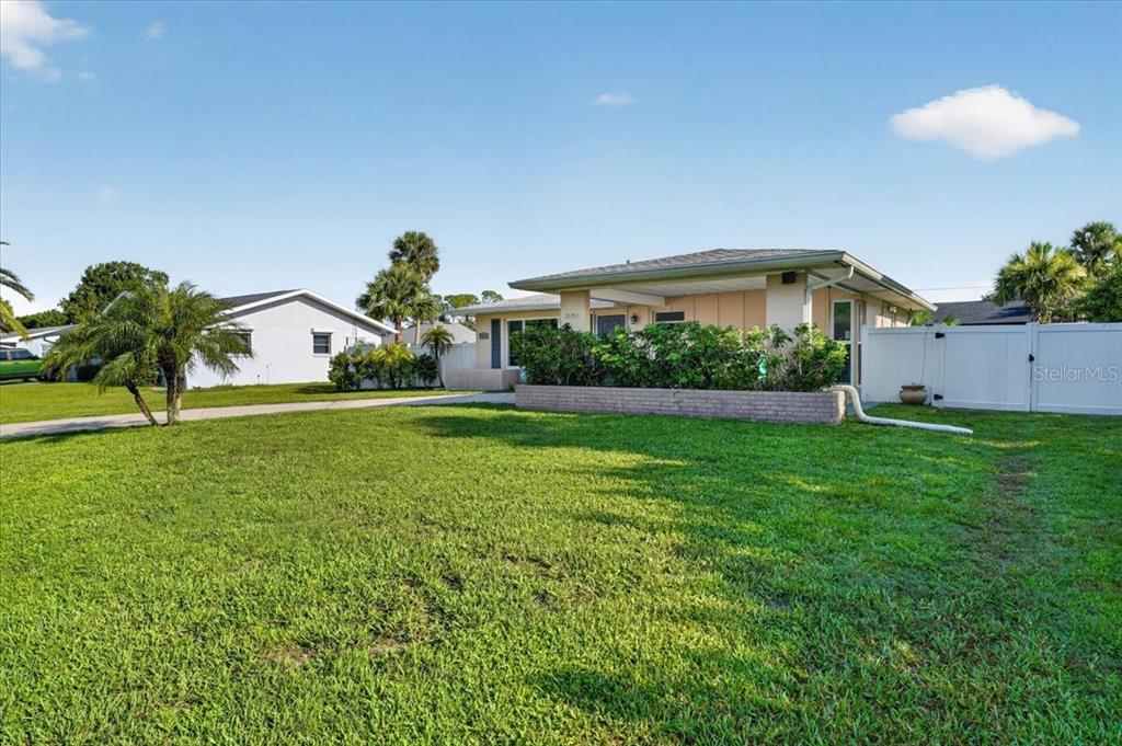 A single-story house with a low-pitched roof, a brick planter, and a white privacy fence — 20286 BENTON AVENUE, PORT CHARLOTTE, FL