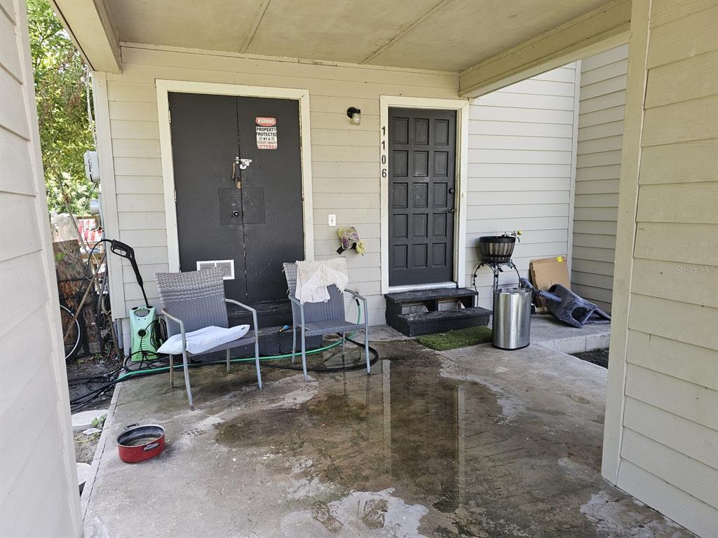 A covered concrete patio features two chairs, a storage closet, and a front door — 1108 COUNTRY CLUB LANE, LAKELAND, FL