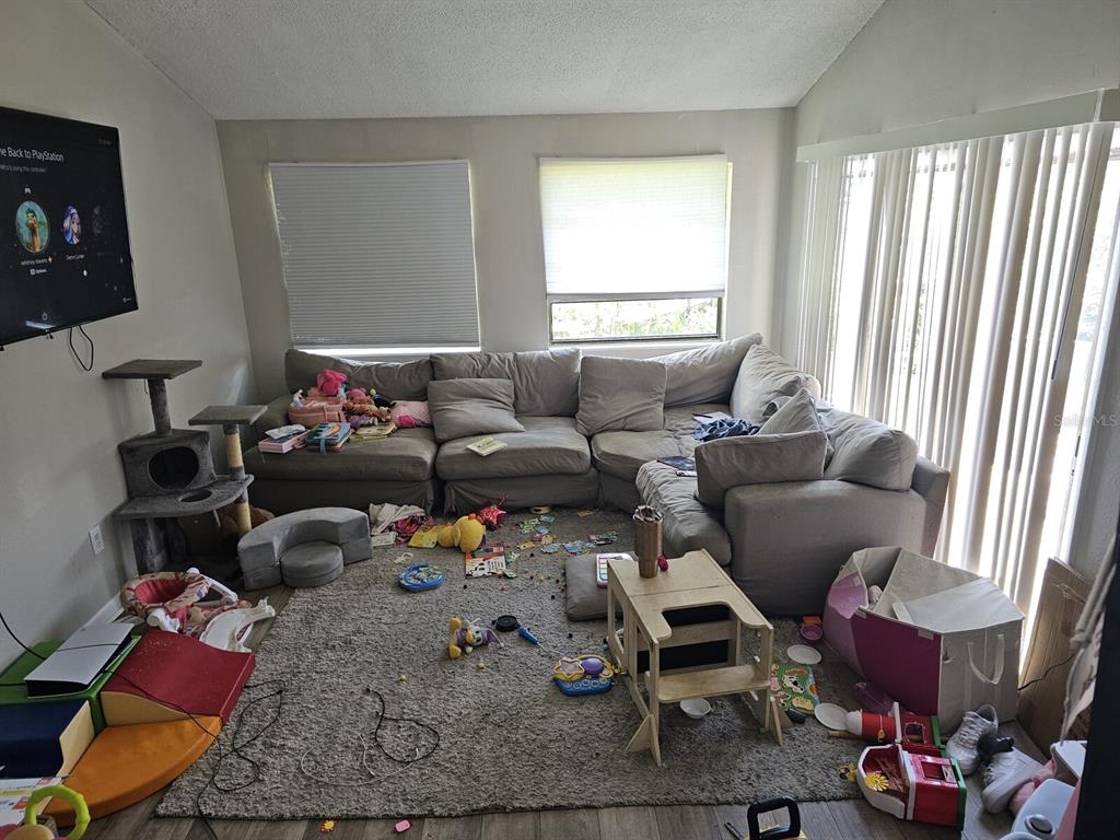 A living room with a large sectional sofa, a gray area rug, and scattered children's toys — 1108 COUNTRY CLUB LANE, LAKELAND, FL