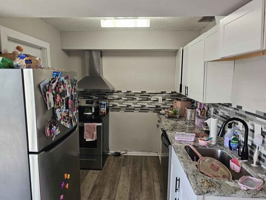 A kitchen features stainless steel appliances, white cabinets, granite countertops, and a tiled backsplash — 1108 COUNTRY CLUB LANE, LAKELAND, FL