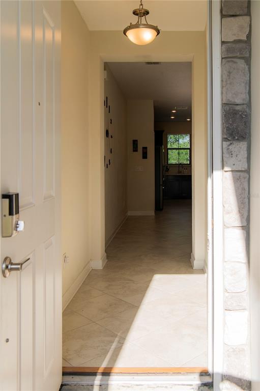 A view through an open front door into a tiled entryway with a hanging light — 11378 WHISTLING PINE WAY, ORLANDO, FL