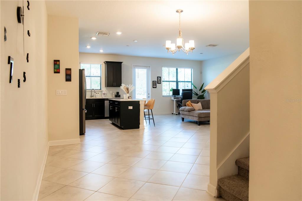 An open-concept kitchen and living area features dark cabinetry, a kitchen island, and tile flooring — 11378 WHISTLING PINE WAY, ORLANDO, FL