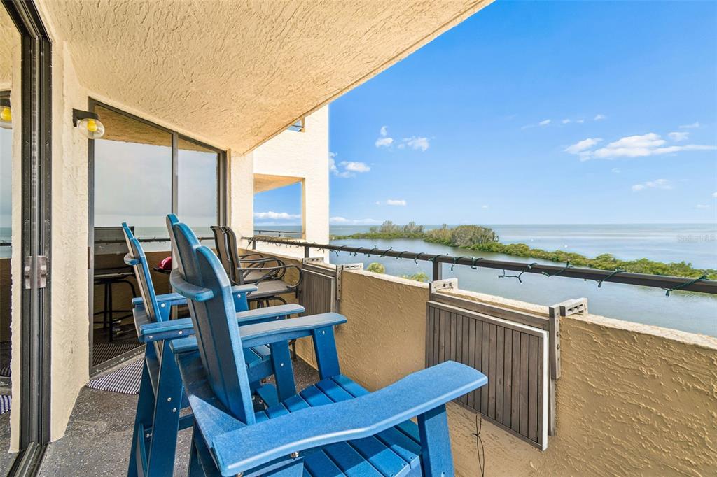 A balcony with blue chairs overlooks a body of water and a mangrove island — 6009 SEA RANCH DRIVE UNIT 503, HUDSON, FL