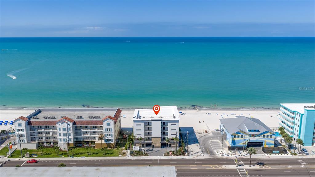 An aerial view shows a multi-story beachfront building with a red location pin on top — 14048 GULF BOULEVARD UNIT 201, MADEIRA BEACH, FL