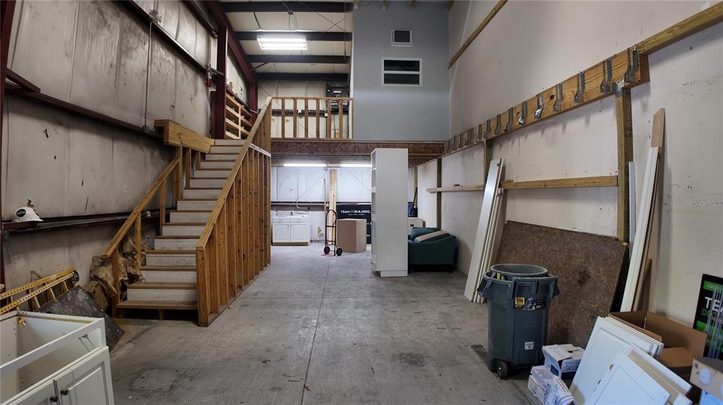 An industrial warehouse space features a wooden staircase leading to a lofted storage area — 2024 PRINCETON STREET, SARASOTA, FL