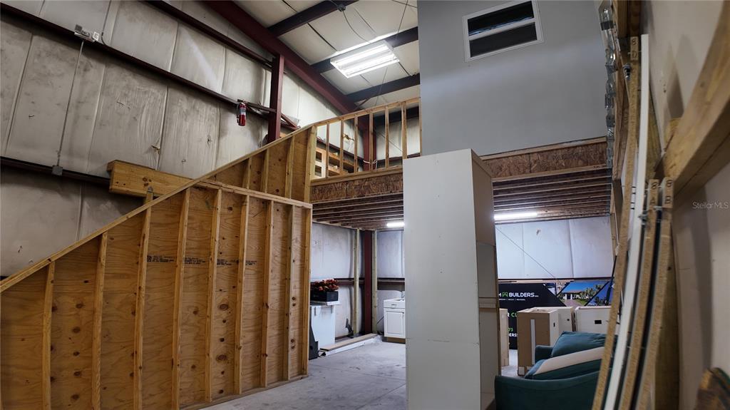 An interior view of a warehouse space featuring a wooden staircase leading to a loft — 2024 PRINCETON STREET, SARASOTA, FL