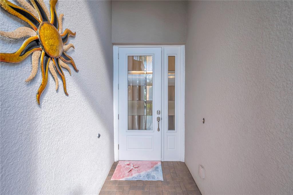 A white front door with glass panels sits in a recessed entryway with brick flooring — 15433 SANTA POLA DRIVE, WIMAUMA, FL