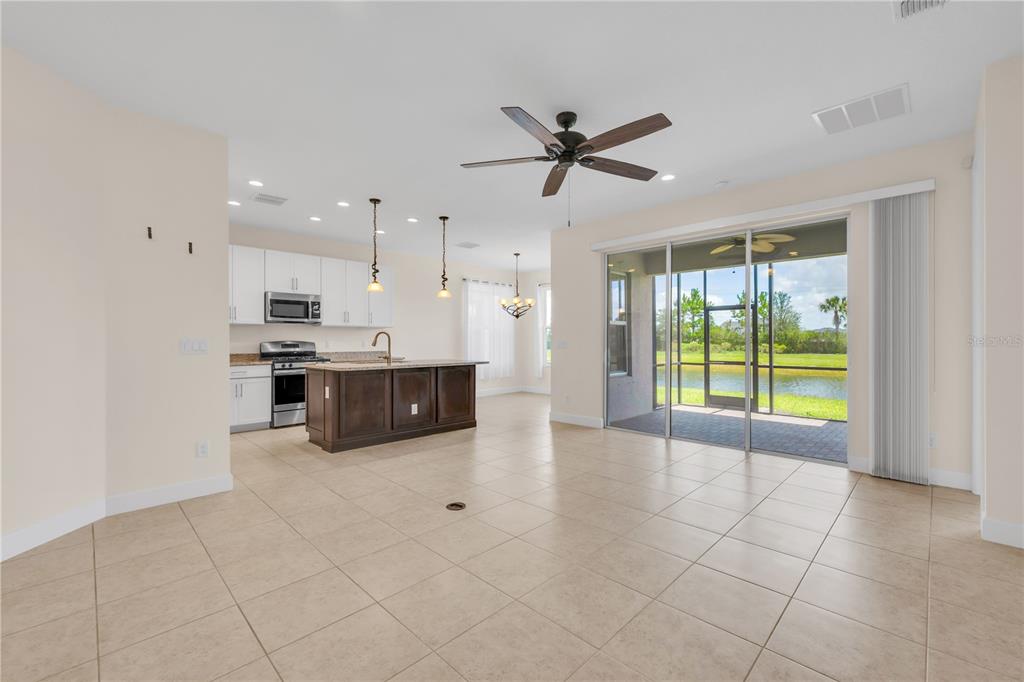 An open-concept kitchen and living area with tile floors, a dark wood island, and patio — 15433 SANTA POLA DRIVE, WIMAUMA, FL