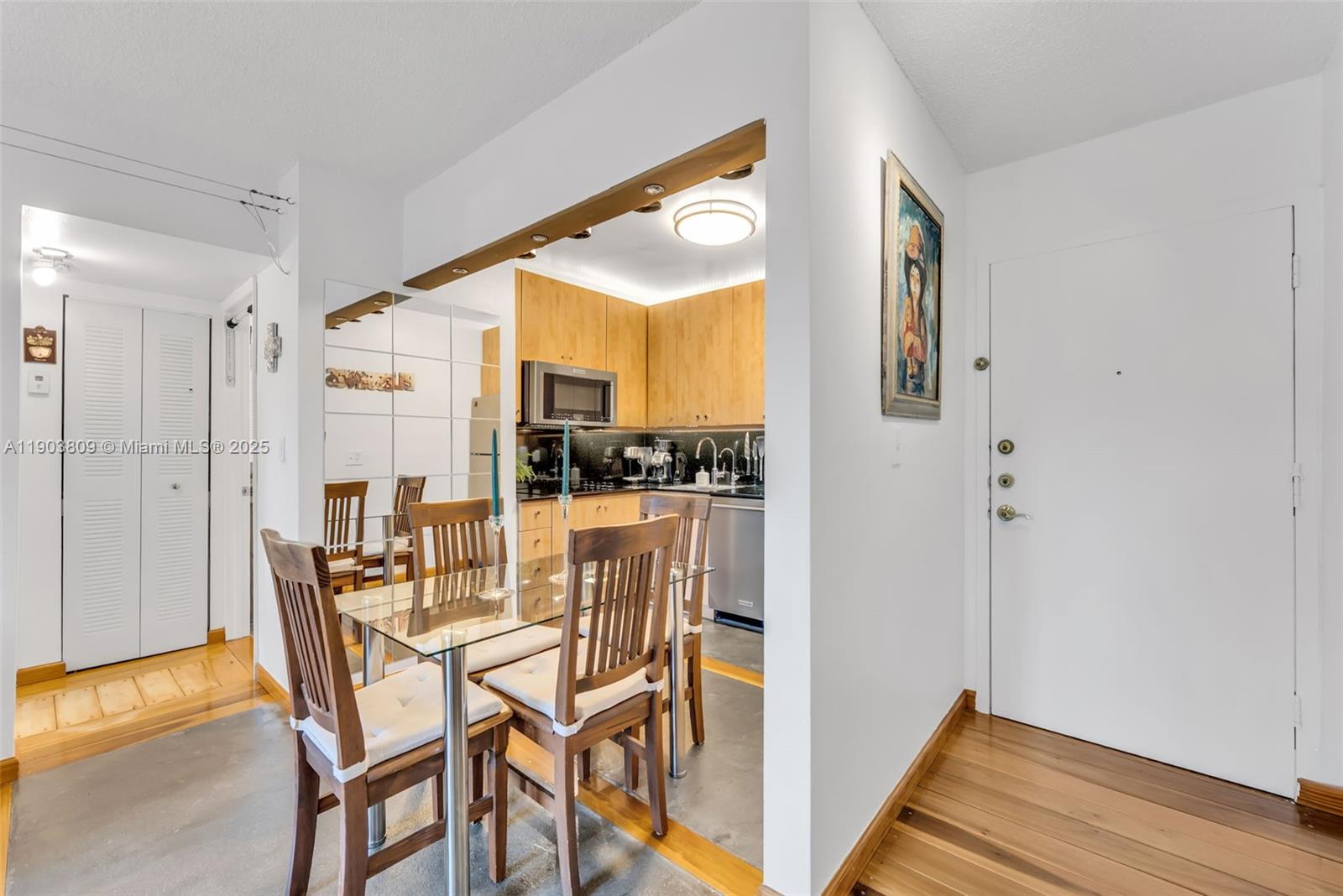 A dining area with a glass table and wooden chairs sits beside a galley kitchen — 3661 SW 9th Ter # 207, Miami FL 33135, MIAMI, FL