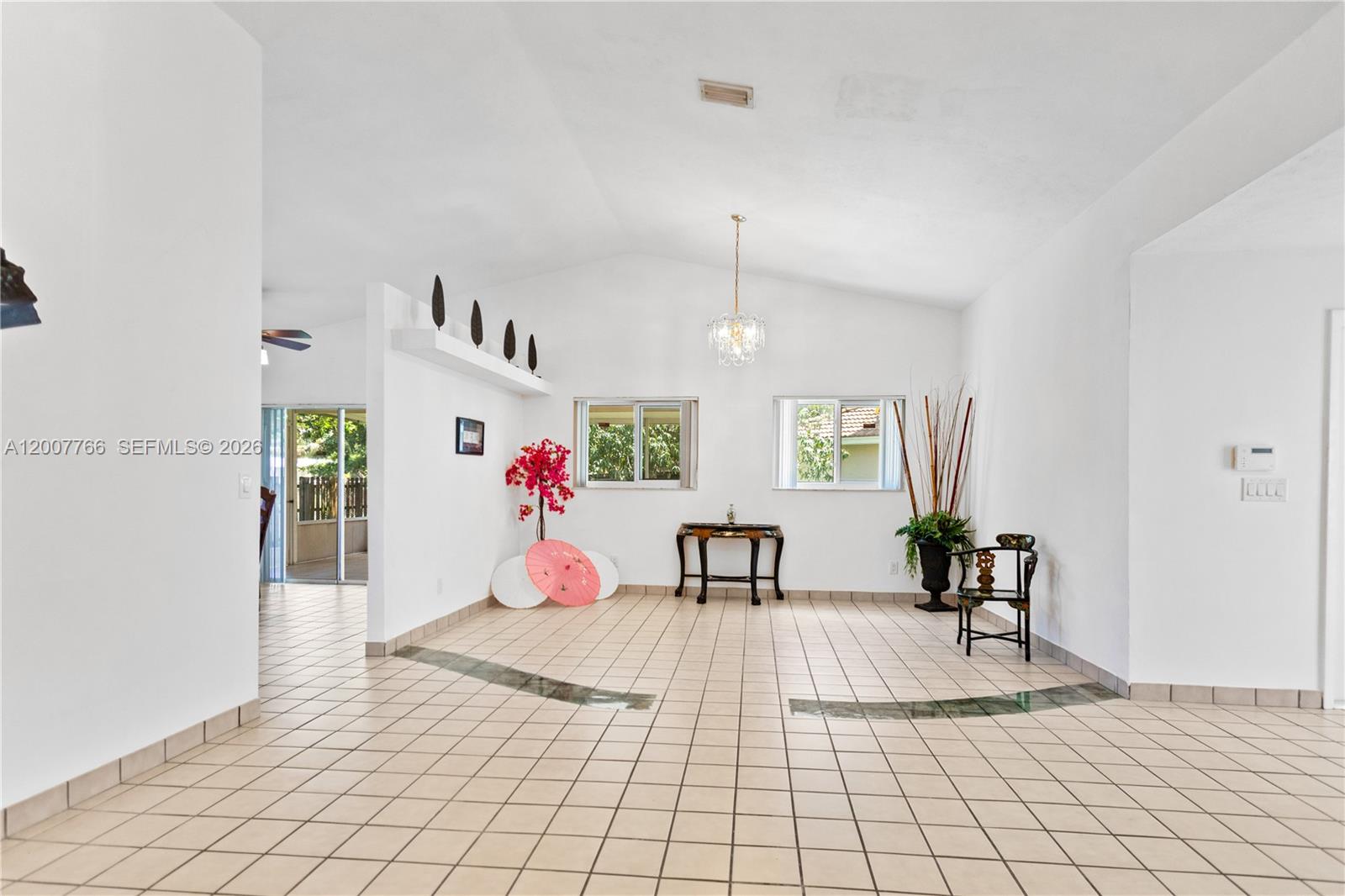 A bright, tiled living area features a vaulted ceiling, two windows, and minimalist decor — 6450 SW 13th St, Plantation FL 33317, PLANTATION, FL