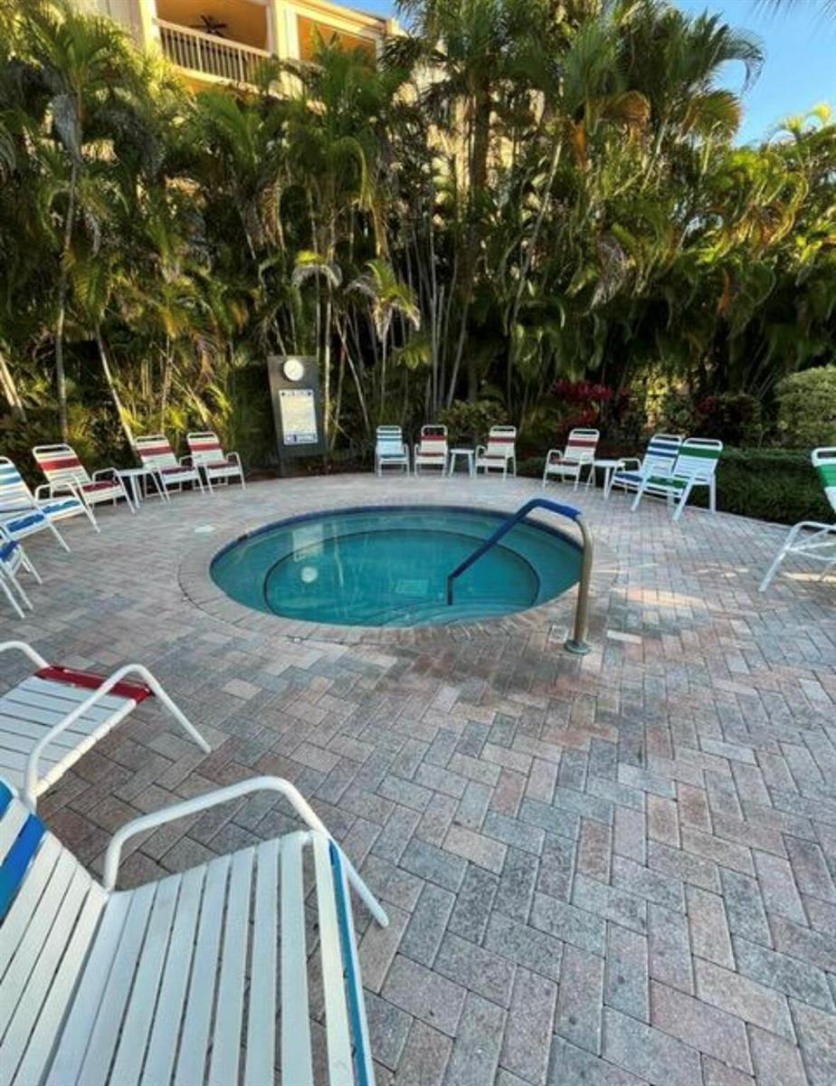 A circular hot tub is surrounded by lounge chairs on a brick patio with palm trees — 600 Egret Circle # 7305, Delray Beach FL 33444, DELRAY BEACH, FL