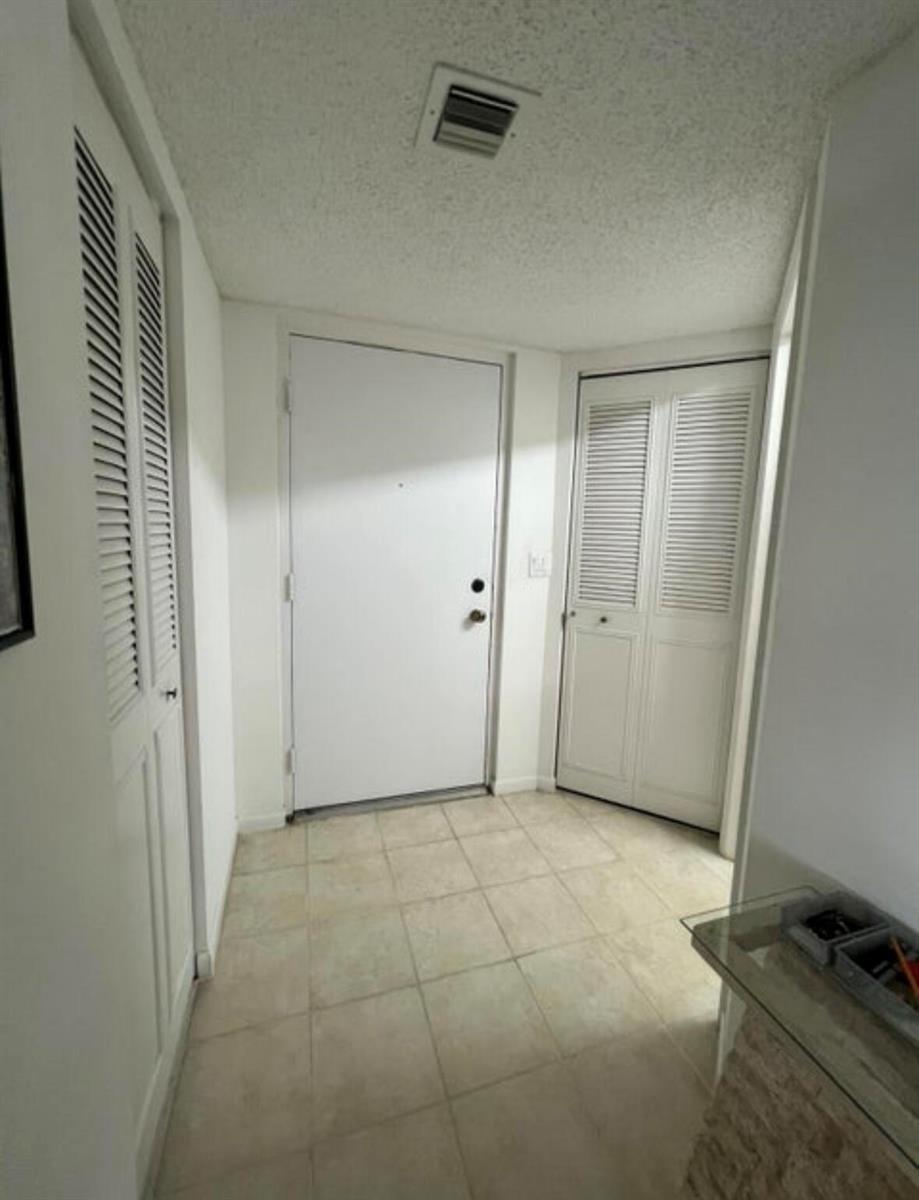 An entryway features a white front door, two louvered closet doors, and light-colored floor tiles — 600 Egret Circle # 7305, Delray Beach FL 33444, DELRAY BEACH, FL