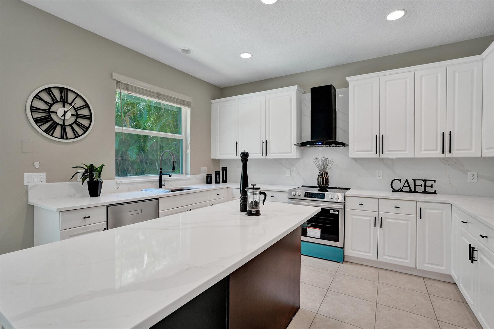A modern kitchen features white cabinets, a central island with a countertop, and stainless appliances — 6020 NW 104th Lane, Parkland FL 33076, PARKLAND, FL